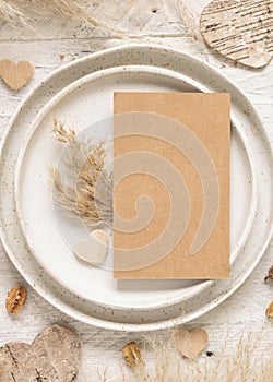 Wedding table place with blank card near dried plants and hearts, mockup
