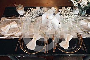 Wedding table set decorated with a selection of tall glass vases containing white flowers.