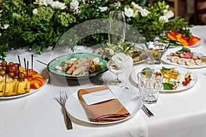 Wedding table setting with blank guest card, napkin, succulent and dish on a wooden plate