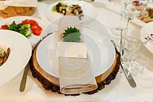 Wedding table setting with blank guest card, napkin, succulent on wooden plate. Rustic decor