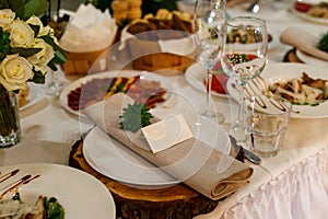 Wedding table setting with blank guest card, napkin, succulent on wooden plate. Rustic decor