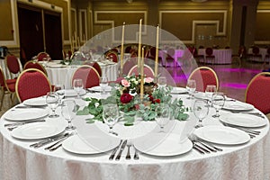 The wedding table setting is decorated with fresh flowers in a brass bowl and golden candles in brass candlesticks. Wedding