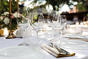 Wedding table setting decorated with fresh flowers in a brass vase. Wedding floristry. Banquet table for guests outdoors with a