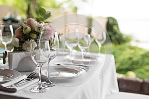 Wedding table setting decorated with fresh flowers in a brass vase. Wedding floristry. Banquet table for guests outdoors with a