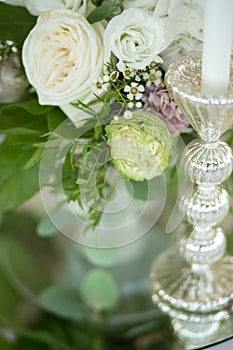 Wedding table setting is decorated with fresh flowers and white candles. Wedding floristry. Bouquet with roses, hydrangea and