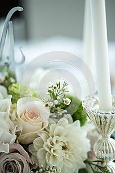 Wedding table setting is decorated with fresh flowers and white candles. Wedding floristry. Bouquet with roses, hydrangea and