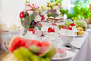 Wedding Table with Sweet White Cake and Strawberry on top. Flowers in Background