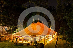 A wedding tent at night surrounded by trees with an orange glow from the lights, long exposure - wedding tent series