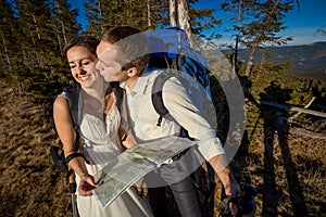 Wedding tourist couple kissing with map in hands. Honeymoon at the mountains