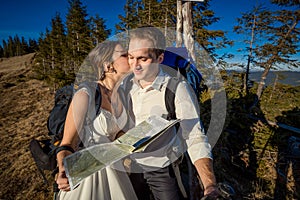 Wedding tourist couple kissing with map in hands. Honeymoon at the mountains