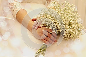 A wedding is a troublesome business: a delicate bouquet in the hands of the bride lies on a wedding dress, close-up, space for