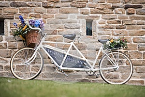Wedding vintage old retro tandem bike with just married sign and fresh flowers in woven basket
