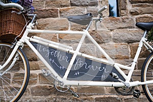 Wedding vintage old retro tandem bike with just married sign and fresh flowers in woven basket.