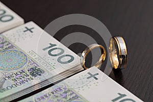 Gold wedding rings surrounded by a stack of Polish banknotes