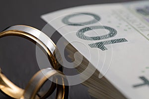 Gold wedding rings surrounded by a stack of Polish banknotes