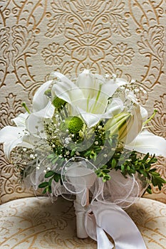 Wedding white bride shoes with a bouquet of white roses and other flowers, wedding rings on a stool