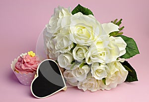 Wedding white roses bouquet with pink cupcake and blank heart sign.