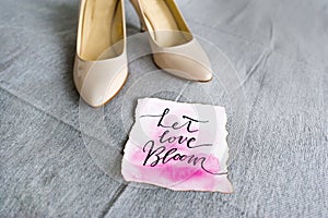 Wedding white shoes and romantic phrase - let love bloom.