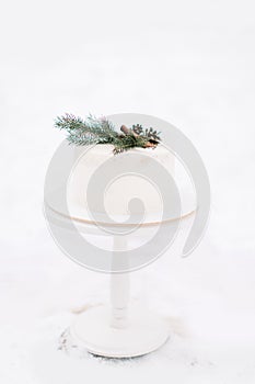 Wedding winter outdoors decorations. White wedding cake decorated with pine branch, cones and cinnamone, on the on white photo