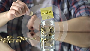 Wedding word above glass jar with money, savings concept, investment in future