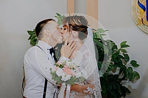 Wedding: young couple in love bride and groom hugging each other holding a bouquet of flowers. Two lovers hearts on the