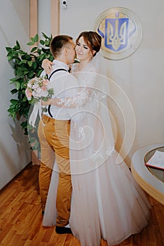 Wedding: young couple in love bride and groom hugging each other holding a bouquet of flowers. Two lovers hearts on the