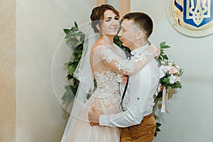 Wedding: young couple in love bride and groom hugging each other holding a bouquet of flowers. Two lovers hearts on the