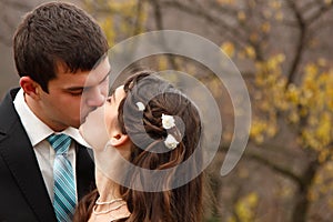 Wedding, young groom kiss bride in love over autumn nature backg