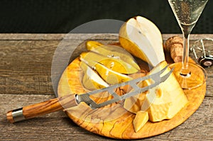 Wedge of cheese, cheese knife, and pear as pairings for a french wine tasting event