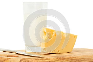 Wedge of cheese, glass of milk and knife on a cheese board