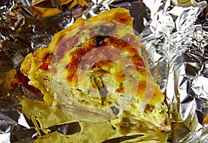 Wedge of quiche lorraine on aluminum foil