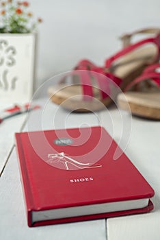 A wedges shoes, a book and a wristwatch in red theme