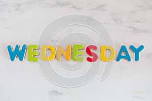 Wednesday word written with colorful letters on white marble stone background