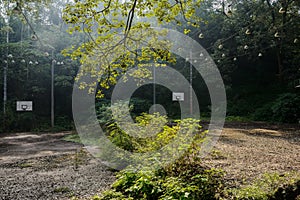 Weedy basketball floodlit courts in abandoned 1960s` factory