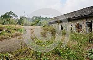 Weedy curving ramp before abandoned 1960s` tile-roofed building