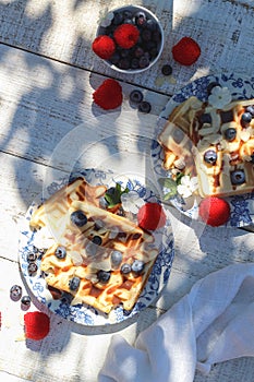 Weekend breakfast table - waffles with summer berries under harsh light