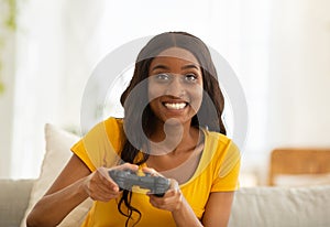 Weekend entertainments. Happy black lady with joystick playing online computer games indoors