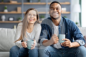 Weekend Leisure. Cheerful young multicultural couple relaxing in living room