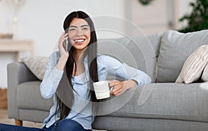 Weekend Leisure. Korean Girl Talking On Cellphone And Drinking Coffee At Home