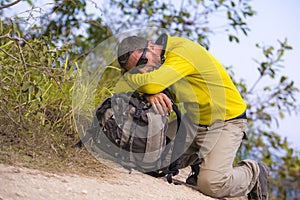 Weekend outdoors - young happy and attractive hiker man with backpack tired and exhausted enjoying hiking activity and nature in