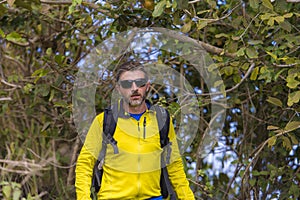 Weekend outdoors - young happy and attractive hiker man with backpack walking around in the wood enjoying hiking activity and