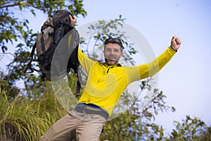 Weekend outdoors - young happy and attractive hiker man with backpack walking around in the wood enjoying hiking activity and