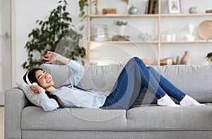 Weekend Passtime. Cheerful Asian Lady Enjoying Listening Music At Home, Wearing Headphones