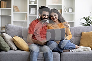 Weekend Passtime. Happy Indian Couple Using Laptop Computer At Home Together