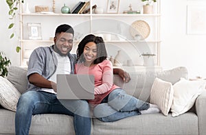 Weekend Passtime. Married Afro Couple Using Laptop At Home Together, Watching Movies