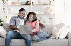 Weekend Passtime. Married Afro Couple Using Laptop At Home Together, Watching Movies photo