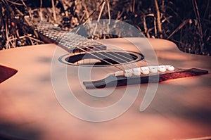 The guitar lies on the ground among the autumn grass and is freshened by the sun. Eye level shooting. Soft focus.