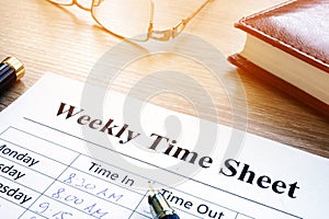 Weekly time sheet and pen on a desk.
