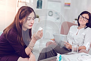 Weeping sorrowful emotional young woman crying and holding paper tissue