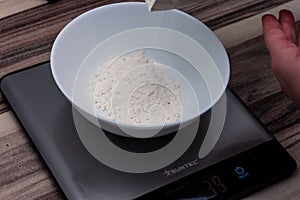 Weighing flour for baking with professional scales on the table